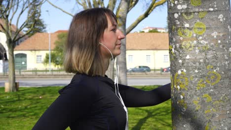 Sportliche-Junge-Frau-Mit-Kopfhörern-Trainiert-Im-Park